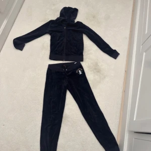 Matchande mjukis  set från Juicy Couture - Säljer en marinblå hoodie och matchande byxor från Juicy Couture. Hoodien har dragkedja och byxorna har en broderad logga på höften samt matchande på ryggen Perfekt för en avslappnad och stilren look. Mycket god kvalitet och står storlek 14 år. 