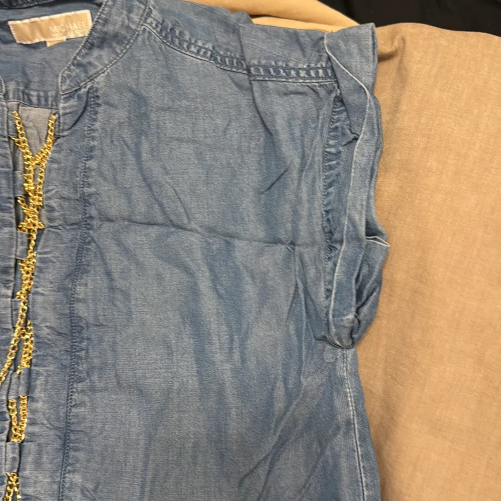 Säljer en snygg blå jeansklänning från Michael Kors i storlek XS. Klänningen har korta ärmar och en cool snörning framtill som ger en unik touch. Perfekt för en avslappnad stil med en touch av elegans. 💙. Mekot.