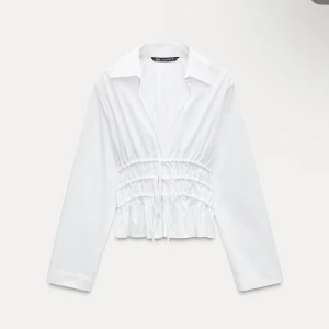 Vit blus från Zara - Snygg vit blus från Zara med knytning framtill och elastisk midja. Blusen har långa ärmar och en  krage. Helt ny med prislapp💕