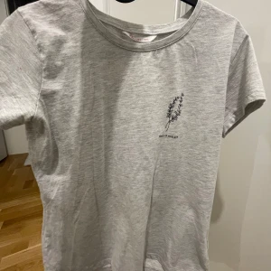 Grå t-shirt med tryck - Snygg grå t-shirt med ett enkelt tryck av en växt och text