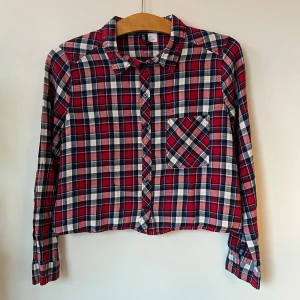 Rutig skjorta - Rutig skjorta i rött, blått och vitt från H&M Divided. Croppad och rak passform. I storlek 40, men har funkat som lite bekvämt löst och oversized för någon som har storlek 36/S. Helt utan defekter och i mjukt material! Jättefin tillsammans med snickarbyxor eller ett par jeans. 