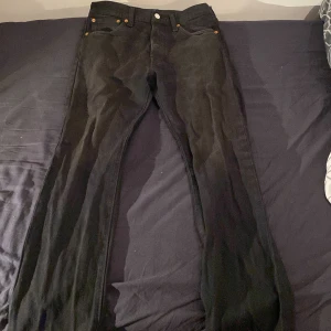 Svarta Levi's 501 jeans - Säljer ett par klassiska svarta Levi's 501 jeans. De har en rak passform och är tillverkade i slitstarkt denim. Perfekta för en stilren look med knappgylf och fem fickor.