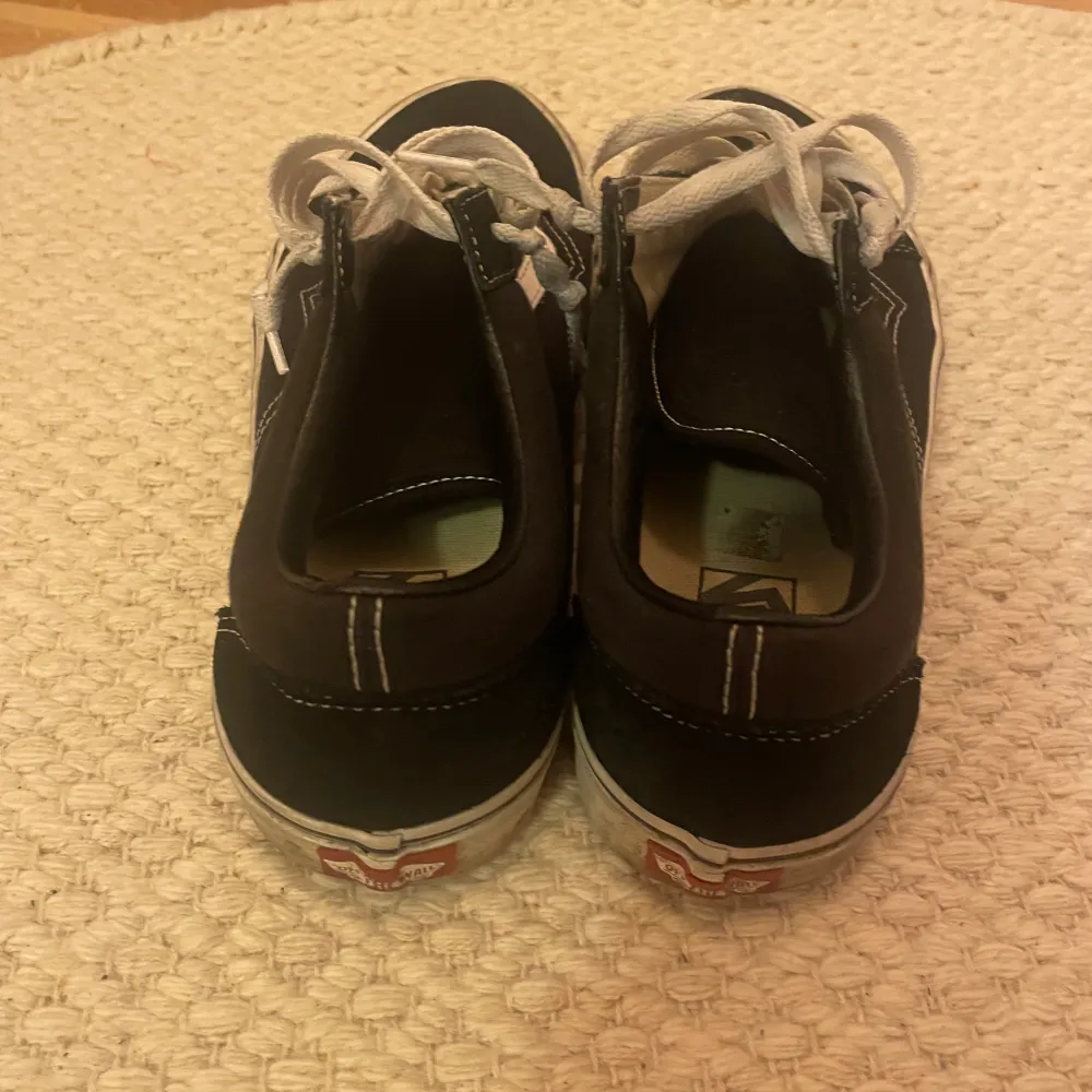 Säljer ett par klassiska svarta Vans sneakers med vit sula och vita snören. Storlek 45. Kengät.