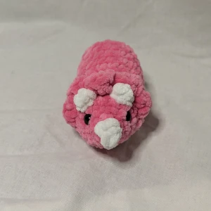 Rosa triceratops  - Söt rosa triceratops med vita detaljer och svarta ögon. Perfekt som en mjuk och gosig kompis.