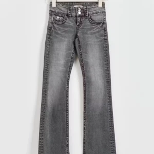 Grå bootcut jeans - Snygga grå bootcut jeans med låg midja och klassisk femficksdesign. Jeansen har en diskret tvättad look och stängs med dragkedja och knapp. Perfekta för en avslappnad stil.