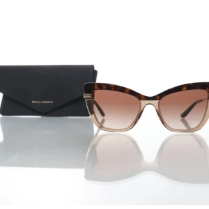 Solglasögon från Dolce & Gabbana - Snygga solglasögon från Dolce & Gabbana med en elegant kattögonform. Bågarna har ett trendigt leopardmönster och glasen är tonade i brunt. Perfekta för att ge en touch av glamour till din stil.