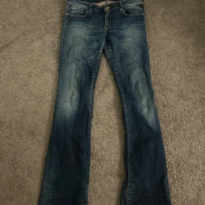 Blå jeans från Replay - Snygga blå jeans från Replay med en läderpatch med Replay-logga på baksidan. Lågmidjade och bootcut. L 32