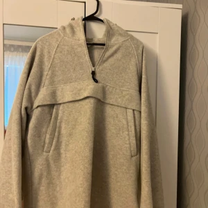 Arket Grå fleece hoodie - Mysig grå hoodie i fleece med dragkedja och huva från Arket. Perfekt för kyliga dagar med sin mjuka och varma känsla. Den har en enkel design med långa ärmar och en praktisk ficka framtill.