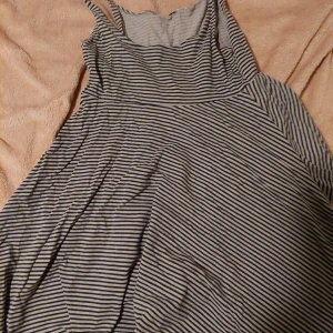 Randig klänning - Snygg randig klänning med smala axelband och en avslappnad passform. Perfekt för en somrig dag eller en avslappnad utflykt. Den har ett klassiskt randigt mönster i svart och vitt.