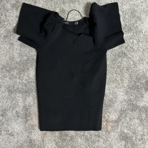 Svart klänning med puffärmar - Elegant svart klänning med korta puffärmar och en stilren design. Perfekt för en chic look.