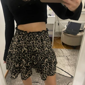 Leopardmönstrad kortkjol - Snygg leopardmönstrad kjol med volang detaljer. Kjolen har en elastisk midja och går att använda som hög och lågmidjad