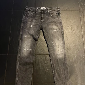 Replay jeans - Snygga grå jeans från Replay i modellen Anbass. De har en slim passform och är tillverkade i denim med slitna detaljer för en trendig look. Perfekta för en avslappnad stil.