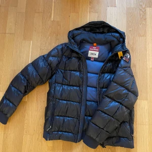 Sheen, dunjacka från Parajumpers - Säljer en svart dunjacka från Parajumpers, modell Sheen. Jackan har använts en del och deffekterna visar på bilderna. Därav priset för en super fin jacka. Äkta.