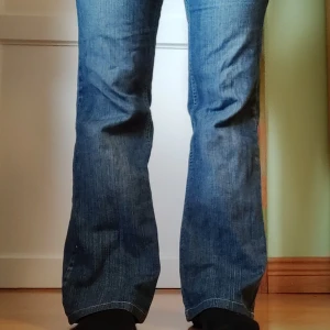 Blå bootcut jeans - Snygga blå bootcut jeans med klassisk femficksdesign.. Perfekta för en avslappnad stil med en touch av retro. De har en bekväm passform och är tillverkade i slitstarkt denim. Korta, passar folk under 160.