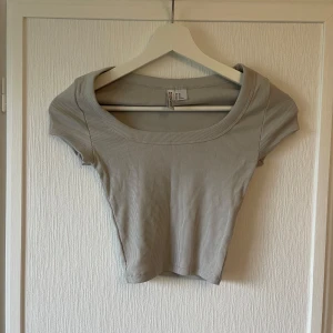 Ljusgrå ribbad topp - Säljer en stilren grå ribbad topp med korta ärmar. Perfekt för en avslappnad look. Toppen har en rund halsringning och är i storlek XS. Den har aldrig riktigt blivit använd då den är för liten för mig. Har gått sönder pytte lite på tredje bilden. 