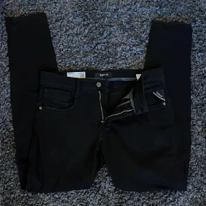 Svarta jeans från Replay - Snygga svarta Replay Anbass jeans med slim fit. De har en klassisk femficksdesign och dragkedja. Perfekta för en stilren look. Storlek 32/32 men lite små i storleken