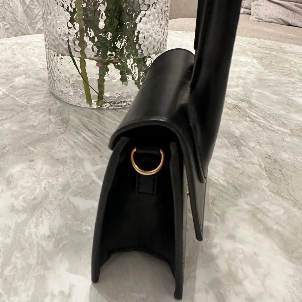 Snygg och kompakt svart handväska från Jacquemus i skinn. Väskan har ett stilrent och minimalistiskt utseende med ett handtag och en magnetisk stängning. Perfekt för att bära med sig det allra viktigaste.. Laukut & Käsilaukut.