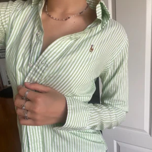 Grön- och vitrandig skjorta från Ralph Lauren - Snygg grön- och vitrandig skjorta från Ralph Lauren med klassisk krage och knappar framtill. Skjortan har långa ärmar och en broderad logotyp på bröstet. Str XXS, men passar perfekt❤️Aldri brukt