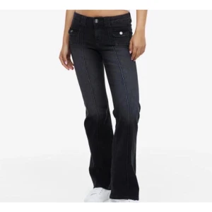Svarta bootcut jeans - Snygga svarta bootcut jeans med låg midja och knappar framtill. Perfekta för en trendig look med sina stilrena linjer och klassiska design. Passar mig som är 166