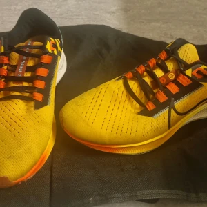 Nike Air Zoom Pegasus 3 i gult och svart - Snygga Nike Air Zoom Pegasus 3 sneakers i en iögonfallande gul färg med svarta och orange detaljer. Skorna har snörning och en bekväm passform, perfekt för löpning eller vardagsbruk.