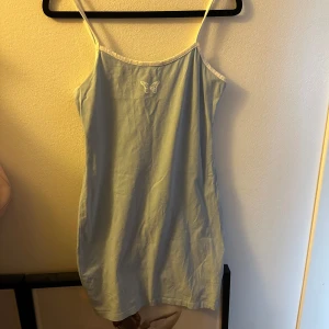 Ljusblå klänning med fjärilsdetalj - Söt ljusblå klänning med smala axelband och en liten fjärilsdetalj på bröstet. Perfekt för varma sommardagar. Enkel och stilren design som passar till många tillfällen.