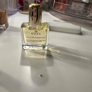 Nuxe Huile Prodigieuse multifunktionell olja - Nuxe Huile Prodigieuse är en lyxig multifunktionell olja för ansikte, kropp och hår. Den kommer i en elegant glasflaska med en gyllene kork. Perfekt för att ge näring och lyster till huden och håret.