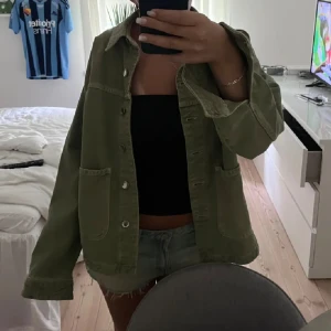 Grön jeansjacka - Säljer en superfin grön jeans jacka. Jackan har en avslappnad passform och stora fickor på framsidan. Den är ifrån Zara och i storleken S.