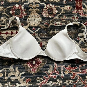 Vit bh från Lindex med rosett! - Säljer en vit bh från Lindex med justerbara axelband och slät design. Den är i storlek 70B, i använt med bra skick!  Perfekt för en bekväm och stilren look. Tillverkad i ett mjukt material för extra komfort.