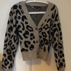 leopardmönstrad kofta  - Säljer en snygg grå/beige kofta med leopardmönster från Kappahl. Koftan har långa ärmar och knappar framtill. Perfekt för att ge din outfit en trendig touch 🐆