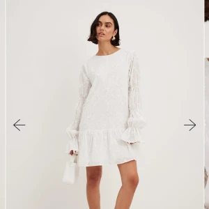 Vit klänning med blommig spets - Vit klänning perfekt till student, midsommar och sommar mm. Den har långa ärmar och en öppen rygg med knytband. Användt 1 gång, fint skick!