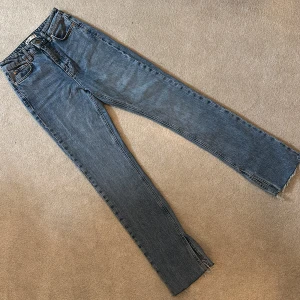 Blå jeans med slits - Snygga blå jeans med en slits vid bensluten. De har en klassisk femficksdesign och en dragkedja med knapp framtill. Perfekta för en avslappnad stil.