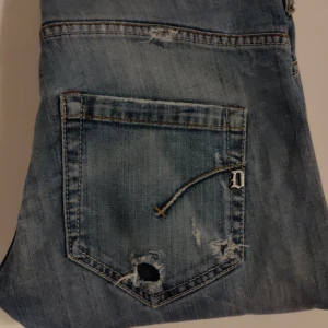 Ljusa slitna jeans från Dondup - Tja! Säljer mina snygga ljusa jeans från Dondup med riktigt schyssta slitningar. Perfekta för en avslappnad stil och passar till allt. Riktigt sköna jeans, finns tecken på användning så skicket skulle jag säga är 7/10. Men om du letar efter dondup för ett bra pris så är dessa perfekta💯