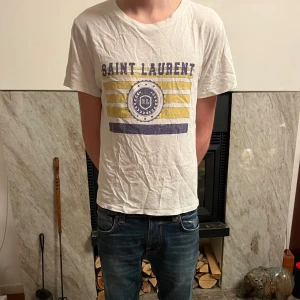 Saint Laurent t-shirt  - Säljer en vit t-shirt från Saint Laurent med najs tryck. Storlek smal, bra skick. Inte mycket mer att säga jävligt fet.