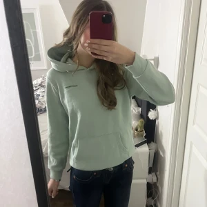 Mintgrön hoodie från Peak Performance - Säljer en snygg mintgrön hoodie från Peak Performance. Den har en klassisk design med en känguruficka framtill och en bekväm huva. helt ny aldrig använd men säljer då den är för liten för mig, materialet är super skönt. Pris kan diskuteras💗