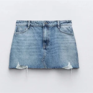 Blå jeanskjol - Trendig blå jeanskjol med slitna detaljer med fin detalj på bakfickan!