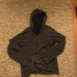 Riktigt fet blå huvtröja från Polo Ralph Lauren - Säljer en unik blå huvtröja från Polo Ralph Lauren med dragkedja och röd broderad logga på bröstet. Hoodien bär en bekväm passform. Riktigt fet!😁skriv vid minsta funderingar. Priset är ej hugget i sten