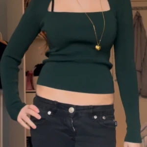 Mörkgrön långärmad topp - Snygg mörkgrön topp med långa ärmar och fyrkantig halsringning. Perfekt för en stilren look. Passar bra till både jeans och kjol.