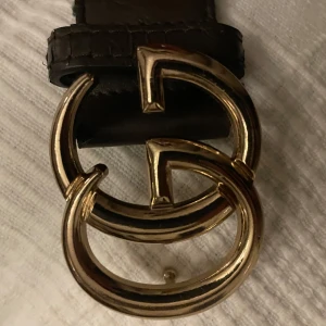 Gucci bälte - Säljer ett Gucci-läderbälte med det klassiska GG-spännet. Bältet är en tidlös accessoar som kombinerar stil och kvalitet, perfekt för både vardag och fest. Det är tillverkat i exklusivt, slitstarkt läder och ger en elegant touch till vilken outfit som helst.