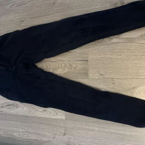 Svarta byxor - Snygga svarta byxor med tight passform. Perfekta för en stilren look. Byxorna har en enkel design med fickor på sidorna.