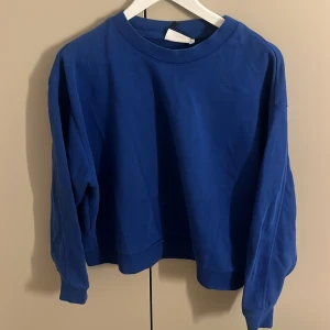 Blå sweatshirt - Säljer en stilren blå sweatshirt med rund hals och långa ärmar. Perfekt för en avslappnad look. Passar bra till jeans eller mjukisbyxor.