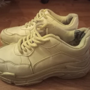 Vita sneakers från NLY Shoes - Säljer ett par vita sneakers från NLY Shoes i storlek 37. Skorna har en klassisk design med snörning och en tjock sula för extra komfort. Perfekta för en avslappnad stil. Köparen står för frakten! 