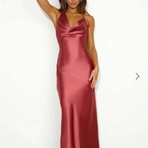 Bal/ långklänning i satin - En mycket fin och oanvänd rosa/röd långklänning i satin med smala axelband och öppen rygg. Klänningen har en vacker glansig yta som ger en lyxig känsla. Perfekt för speciella tillfällen. #balklänning #festklänning #rosaklänning #rödklänning