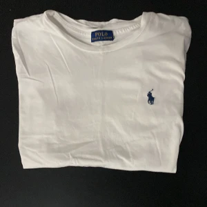 Vit t-shirt från Ralph Lauren - Säljer min ralph lauren t-shirt. Har använt den ganska mycket och den har ett jätte litet hål vid magen men det syns inte alls.
