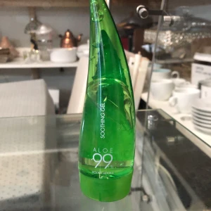 Aloe 99 Soothing Gel från Holika Holika - Aloe 99 Soothing Gel från Holika Holika i en grön, stilren flaska formad som ett aloe vera-blad. Perfekt för att lugna och återfukta huden. Innehåller naturlig aloe vera-extrakt som ger en svalkande känsla.