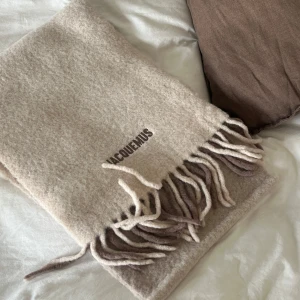 Beige halsduk från Jacquemus - Säljer min superfina beige/bruna halsduk från Jacquemus. Det är en mjuk och varm halsduk i alpacka och ull. Den är perfekt för att hålla dig varm och snygg under kyliga dagar. Den är köpt från FARFETCH och endast använd 1 gång. Inga defekter förekommer💞