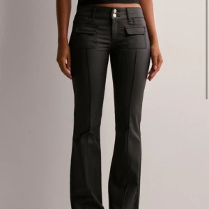 Svarta byxor med fickdetaljer - Snygga svarta byxor med låg midja och bootcut, från Nelly. Byxorna har dubbla knappar framtill och dekorativa fickor. Ord pris 699kr, mitt pris 449kr. Byxorna är som i nyskick då jag använt dom 2 gånger💕 