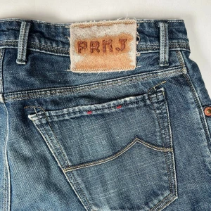 Blå jeansbyxor från Jacob Cohen  - Snygga blå jeansbyxor från Jacob Cohen med klassisk femficksdesign och slitna detaljer. Byxorna har en rak passform och är perfekta för en avslappnad stil. Märkeslappen på baksidan ger en cool touch.