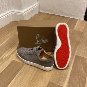 Grå sneakers från Christian Louboutin - Snygga grå sneakers från Christian Louboutin i mocka med den ikoniska röda sulan. Skorna har snörning och en stilren design som passar perfekt för en trendig look. Har använt dom två gånger och tyckte inte att dom var i min stil riktigt! 🎩