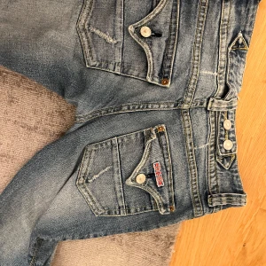 Blå jeans med bootcut - Coola jeans från hudson. Midjemåttet är 34 och passar bra i längden för mig som är 163😗 det saknar knappar men syns inte så mycket när man har dragit upp dragkjedjan. Hållaren för bälte är också sönder men är en snabb fix🩷