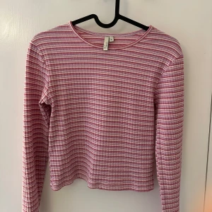 Rosa och vit randig tröja från NLY Trend - Säljer en söt rosa och vit randig tröja från NLY Trend. Tröjan har långa ärmar och en rund halsringning. Perfekt för en avslappnad stil. Hör av dig vid intresse! 🌺